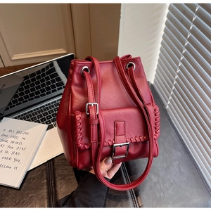 Detailed view of dark red leather bucket bag with silver buckle and braided edge details
