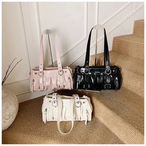 Trois sacs cabas plissés en rose, noir et blanc exposés sur un escalier élégant