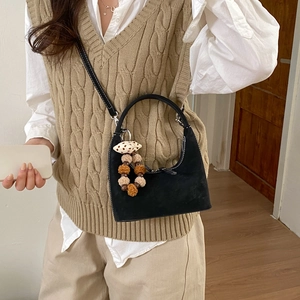 Detail of black dumpling bag with white stitching and plush pompom on a model