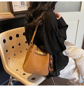 Détail du sac seau vintage en cuir marron avec breloque ethnique en bois et logo doré