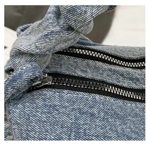 Detail of smooth silver zipper on premium blue washed denim crossbody pillow bag