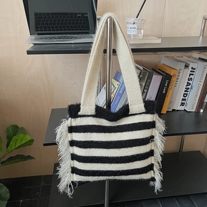 Gros plan du sac cabas en tricot rayé noir et blanc avec de longues franges blanches