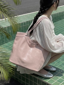 Light pink large capacity tote bag worn on shoulder in a tropical poolside setting