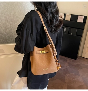 Détail du sac seau en daim caramel avec boucle dorée et breloque en perles de bois bohème