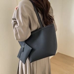 Detail of black pebbled leather tote with contrast white stitching and small pouch bag