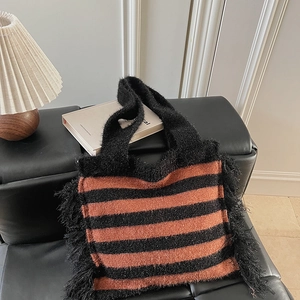 Gros plan du grand sac cabas en maille rayé orange et noir avec des franges sur les côtés