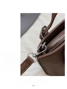 Close-up of brown litchi grain leather texture and silver metal zipper on tote bag