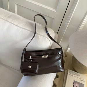Détail d'un sac à bandoulière en cuir marron foncé avec fermoir argenté sur un canapé