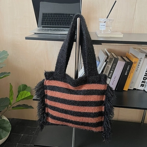 Vue détaillée du cabas en tricot rayé avec franges en plumes noires et texture peluche