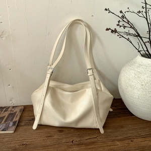 Detailed shot of cream white tote bag with adjustable silver buckle straps and soft texture