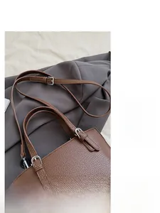 Detail of adjustable shoulder strap and silver buckle on brown lychee leather tote bag