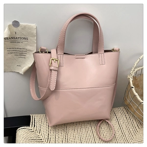 Detail of light pink tote bag featuring smooth leather texture and gold metal buckle