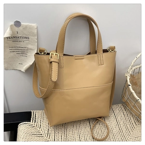Detail view of khaki leather tote bag with adjustable shoulder strap and dual handles