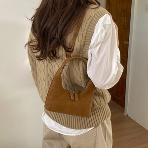 Detail of caramel hobo bag featuring white stitching and smooth matte faux leather finish