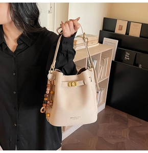 Détail du sac seau beige avec fermoir doré et pendentif en perles de bois bohème