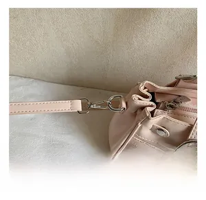Detail of light pink shoulder bag featuring silver metal swivel hooks and side zippers