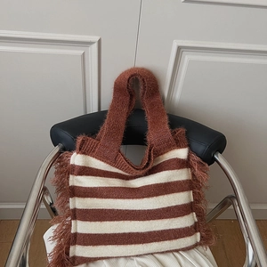 Détail d'un sac cabas en tricot à rayures café et crème avec des franges décoratives