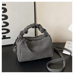 Close-up of pleated handle and denim texture on grey crossbody bag with zippers