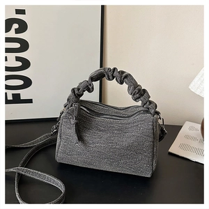 Detail of grey denim boston bag featuring pleated handles and double zip closure