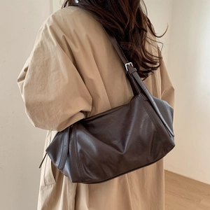 Detailed back view of a large brown soft leather tote bag worn with a beige trench coat