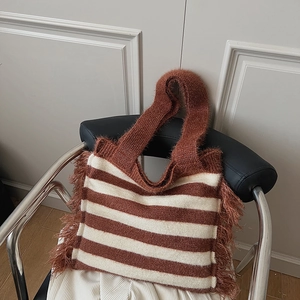 Détail d'un sac cabas en tricot rayé avec franges et finition textile texturée