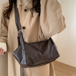Dark brown leather tote bag with adjustable strap worn with a beige trench coat