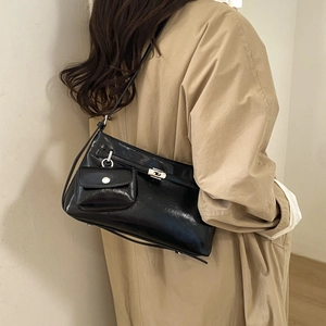 Détail du sac sous le bras en cuir noir brillant avec boucle argentée et mini porte-monnaie