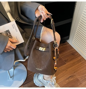 Détail du sac seau marron vintage avec boucle dorée et pompon bohème en perles de bois