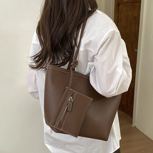 Detail of dark brown tote bag with white contrast stitching and a small matching pouch