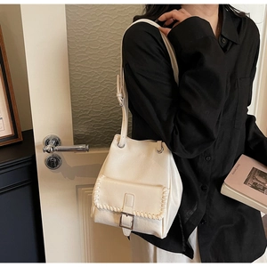 Détail du sac seau blanc crème avec bordure tressée et fermeture à boucle argentée