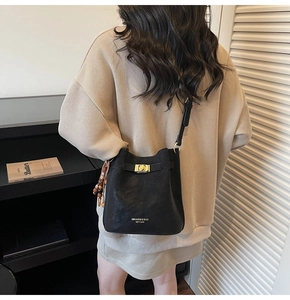 Détail d'un sac seau vintage noir avec fermoir doré et bandoulière réglable pour femme