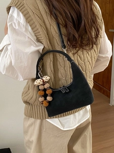 Minimalist black crescent shoulder bag with fuzzy charm shown on a stylish model