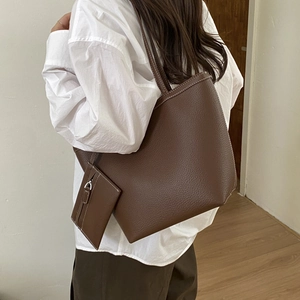 Macro detail of dark brown pebble leather tote bag with white contrast stitching and mini pouch