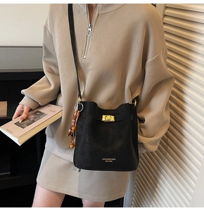 Détail du sac seau en cuir noir avec boucle dorée et pendentif décoratif en perles