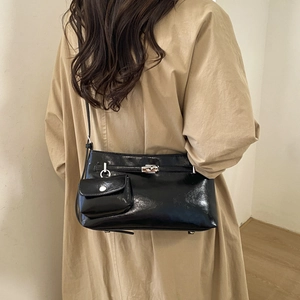 Détail du sac d'épaule noir brillant avec fermoir tournant et mini pochette amovible