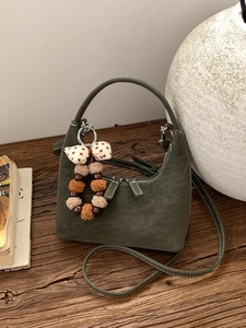 Olive green suede dumpling bag with contrast stitching and beaded bow charm detail