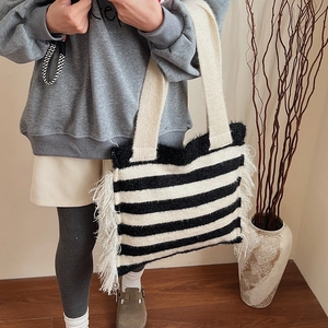 Détail d'un sac cabas en maille rayée noir et blanc avec des franges à plumes