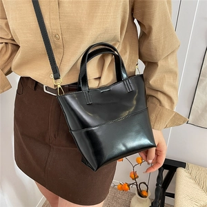 Retro black oil wax leather bucket bag with gold hardware shown on model in cozy setting