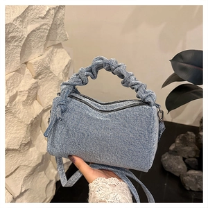 Detail of light blue denim tote with pleated handle and adjustable crossbody strap
