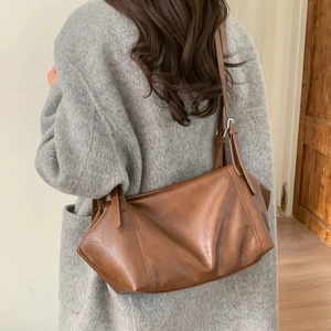 Brown vintage faux leather tote bag with silver hardware worn over a grey tweed coat