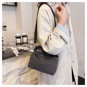 Detail of grey tweed barrel crossbody bag shown on a beige trench coat outfit