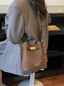 Sac seau rétro marron avec fermoir doré et breloque à perles porté à l'épaule