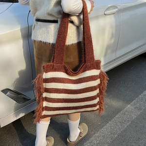 Détail du sac fourre-tout tricoté avec rayures marron et franges douces sur le côté