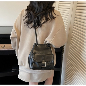 Détail du sac seau noir à cordon avec bords tressés et boucle métallique argentée