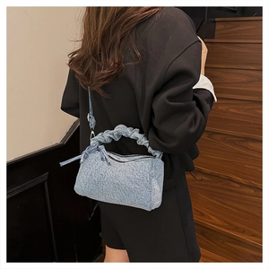 Detail of light blue denim ruched handbag with zip closure and adjustable shoulder strap