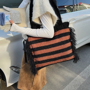 Détail d'un sac cabas en maille rayée avec franges noires et motifs orange et noir brillants