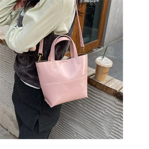 Close-up of a pink patent leather tote bag styled on a window sill for urban fashion