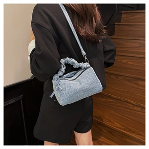 Detail of light blue denim handbag featuring pleated handle and detachable shoulder strap