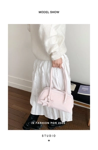 Detailed view of light pink bowling handbag with star charms and slim handles on a model