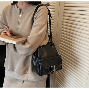Détail du sac seau en cuir noir avec surpiqûres décoratives et fermoir à rabat aimanté